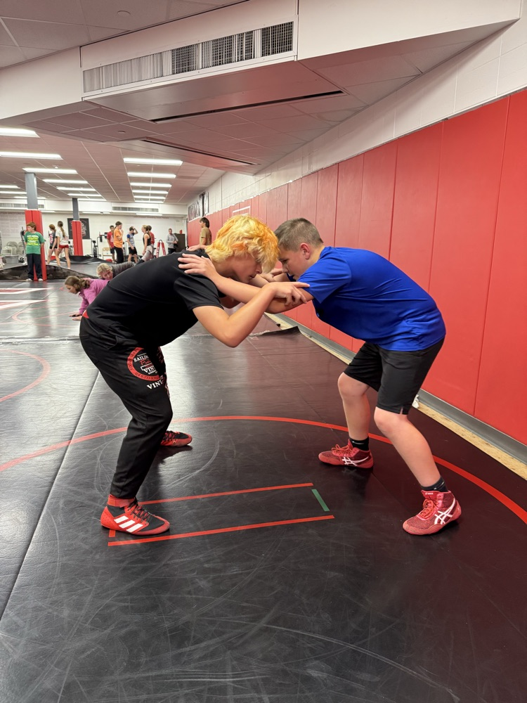 Two boys wrestling on a black wrestling mat