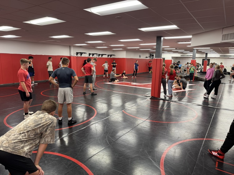 Middle school wrestlers, watching a coach demonstrate a position