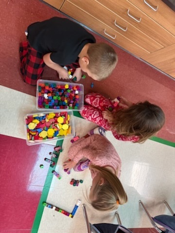 Kindergarten students using various materials to build structures. 