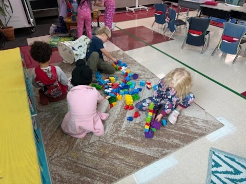 Kindergarten students using various materials to build structures. 