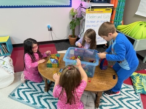 Kindergarten students using various materials to build structures. 
