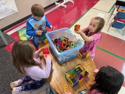 Kindergarten students using various materials to build structures. 