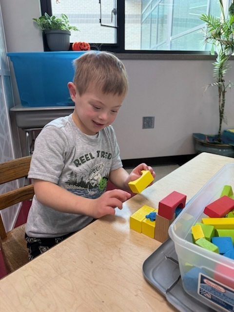 Kindergarten students using various materials to build structures. 