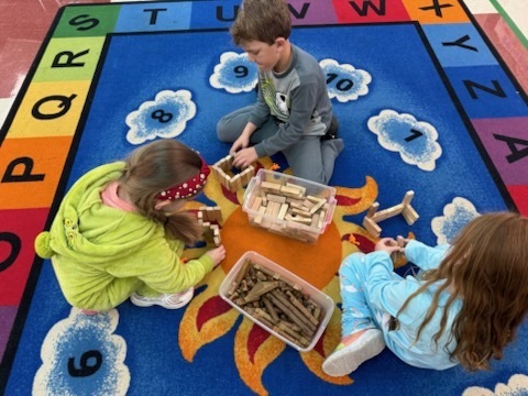 Kindergarten students using various materials to build structures. 