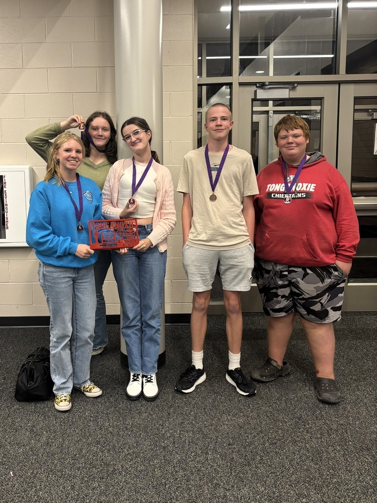 five high school students wearing gold medals on purple ribbons stand in the hallway of a high school