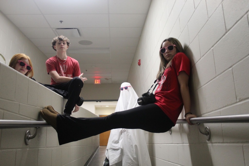 five students in  a cinderblock hallway, one is dressed as a ghost