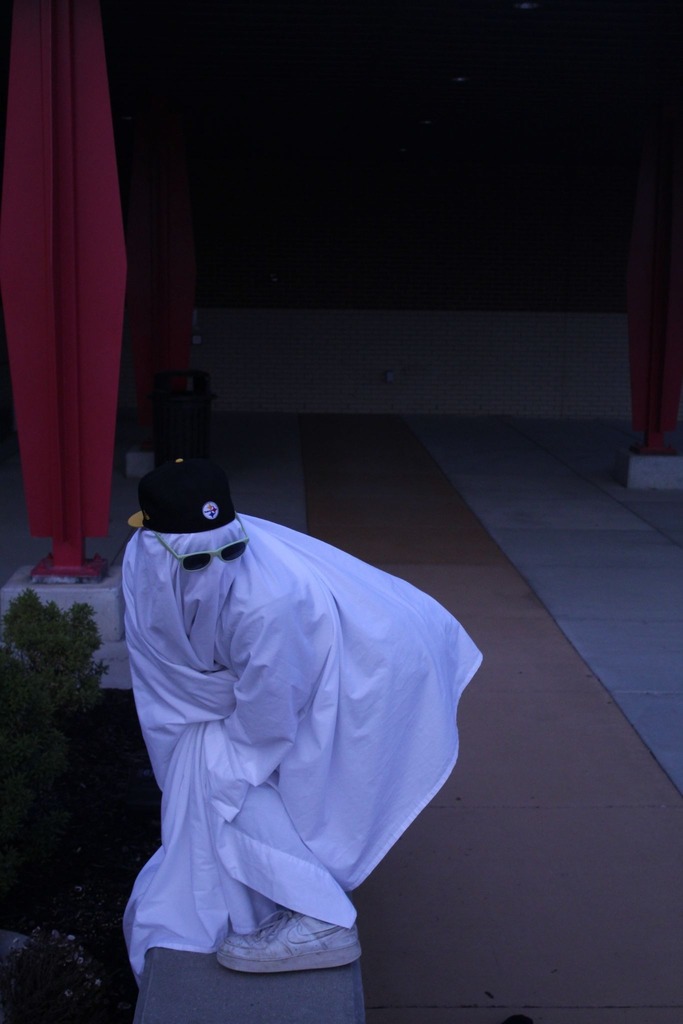 student dressed as a ghost, wearing sunglasses and a black hat