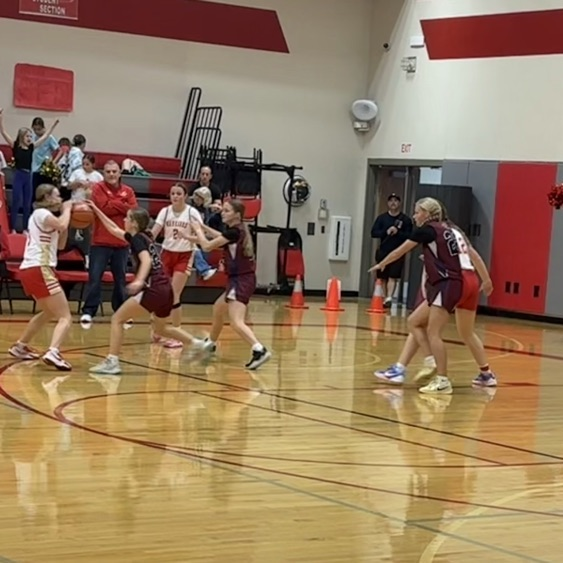girls setting up basketball play at top of key.