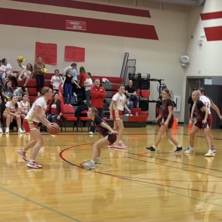 girls in white jerseys playing offense.