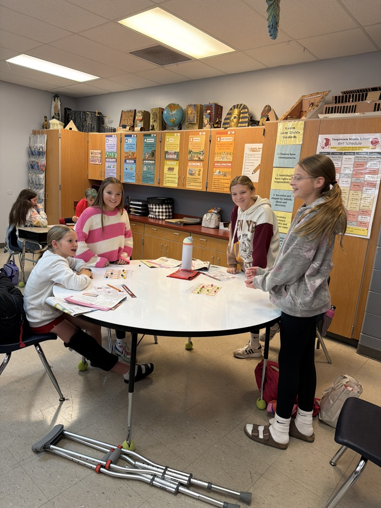 four sixth grade girls sit around a gray circle table in a classroom