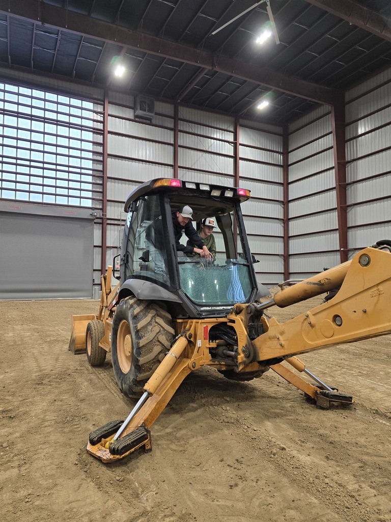 two men in the cab of a yellow construction vehicle