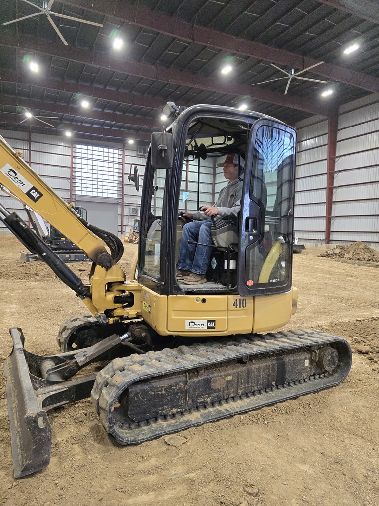 a boy in a gray shirt and jeans operates a bulldozer