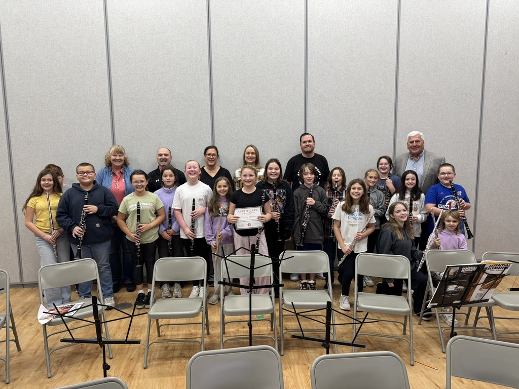 Claire stands with the rest of her band classmates in front of a gray acoustic wall