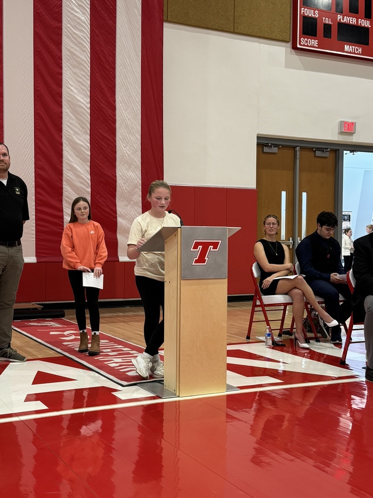 Claire stands at a podium in Chieftain Arena during the Veterans Day Ceremony