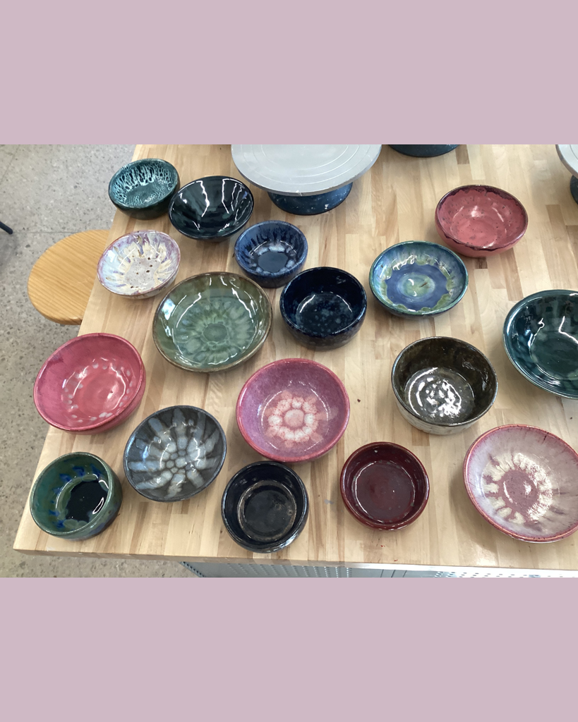 various pottery bowls of different colors and sizes sitting on a wooden tabletop