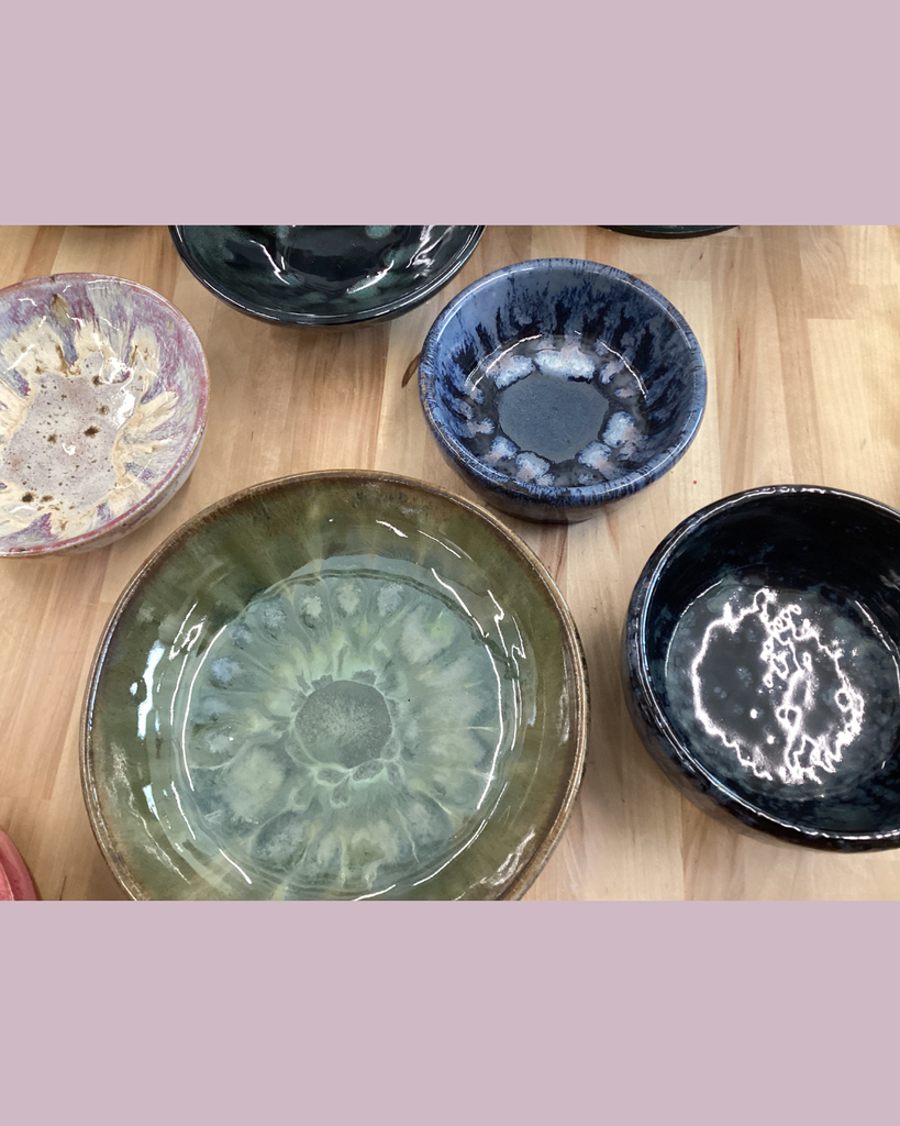 various pottery bowls of different colors and sizes sitting on a wooden tabletop