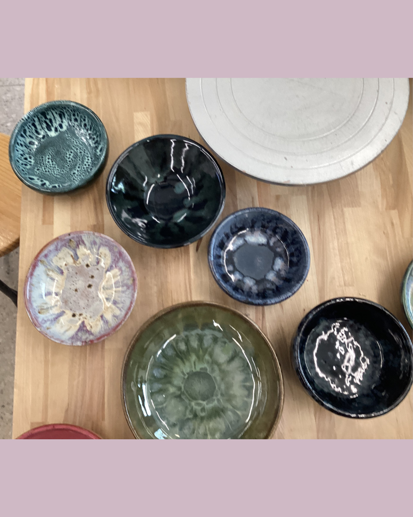 various pottery bowls of different colors and sizes sitting on a wooden tabletop