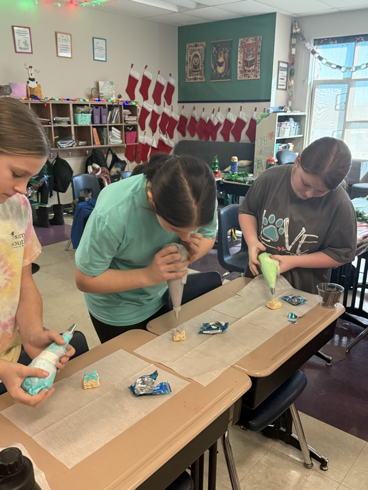 three fifth graders using piping tubes to ice a rice krispie treat
