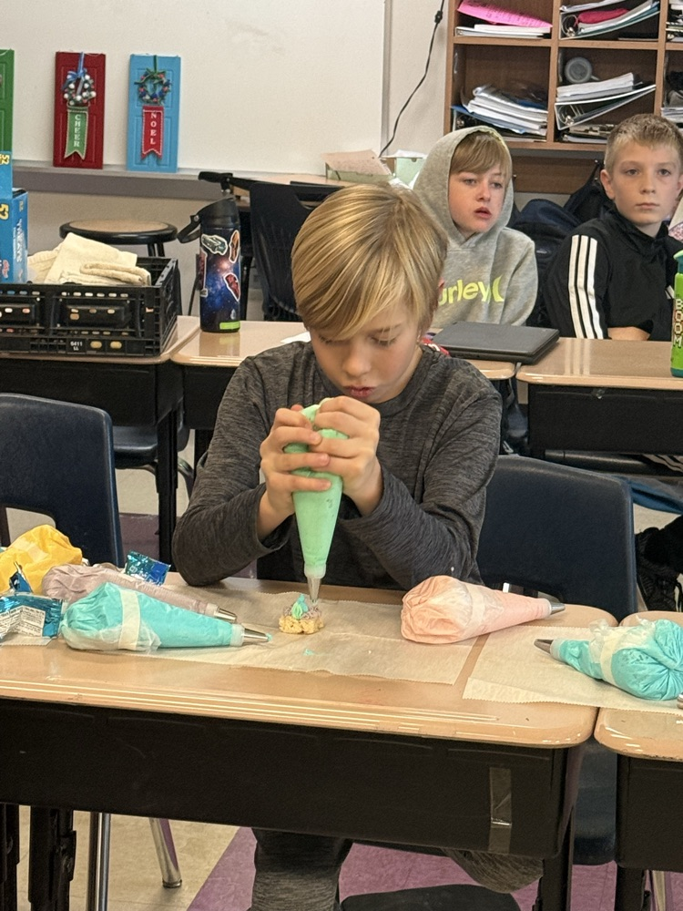 fifth grade boy using piping tube to ice a rice krispie treat