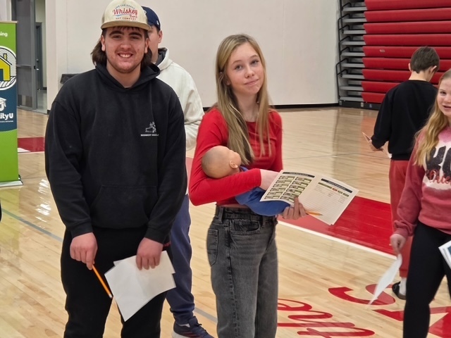 Boy student and girl student walk around to different tables at Reality U.