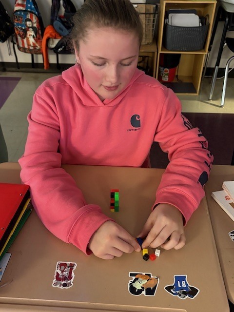 Students in Mrs. Maize's math class use math manipulatives to create a conceptual understanding of finding the volume of a rectangular prism.