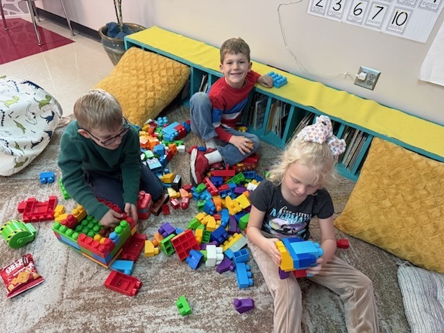 Students using large legos to create a leprechaun trap.