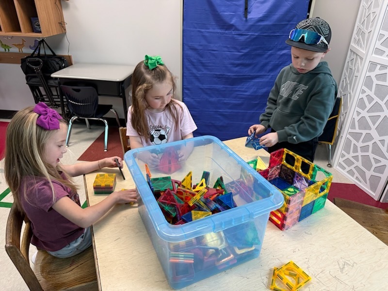 Students using magnet tiles to create a leprechaun trap.