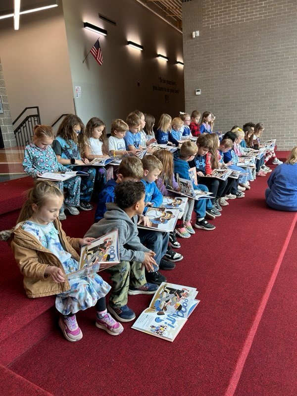 Kindergarten students listening to a teacher read their new book from the Royals Reading Foundation.