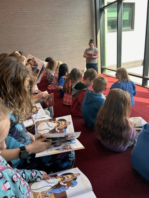 Kindergarten students listening to a teacher read their new book from the Royals Reading Foundation.