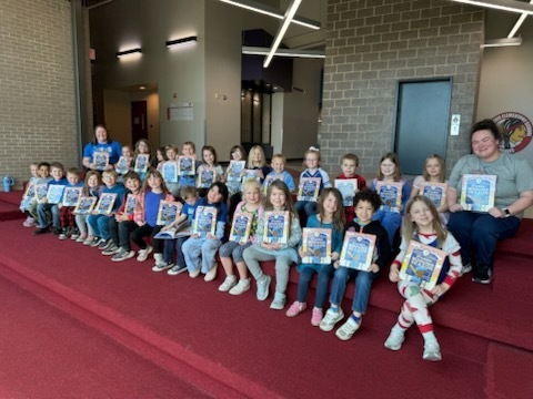 Kindergarten students and their teachers sitting with their new book from the Royals Reading Foundation.