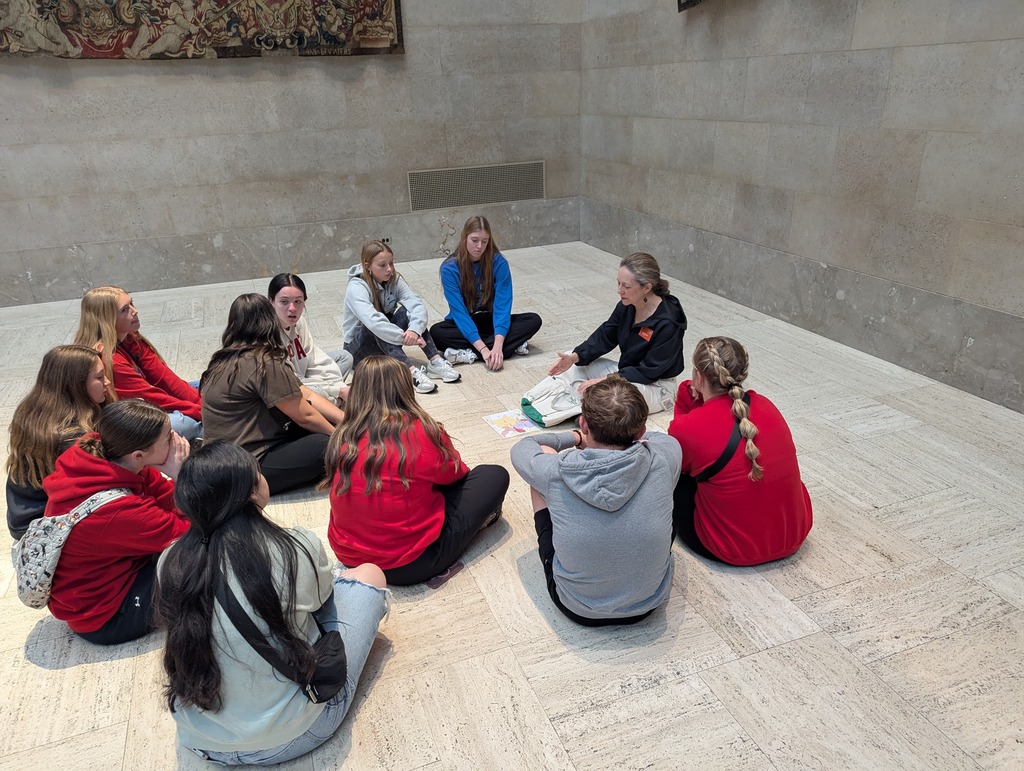 People looking at a docent while she talks about the art