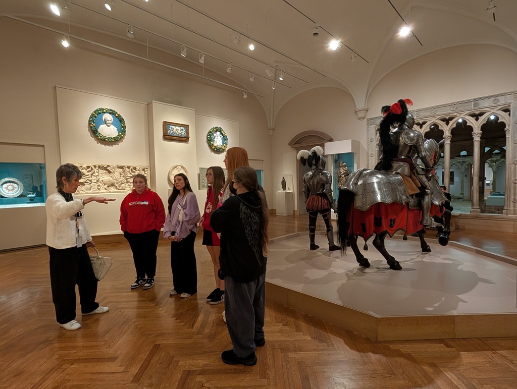 People looking at a docent while she talks about the art