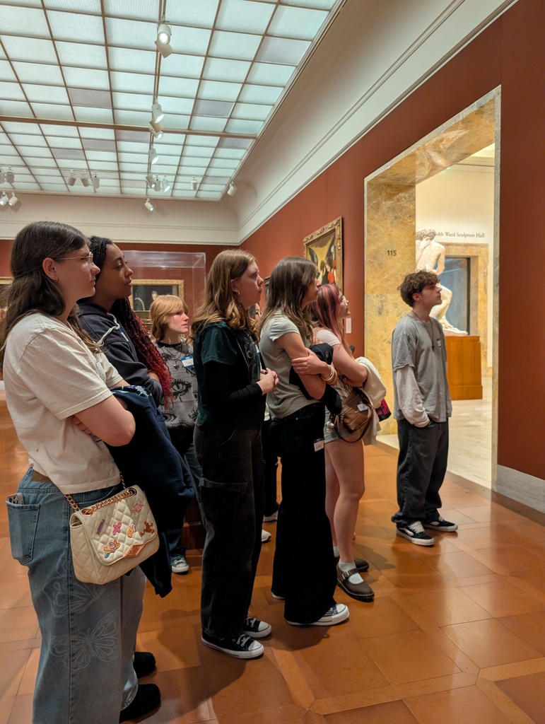 People looking at a docent while she talks about the art