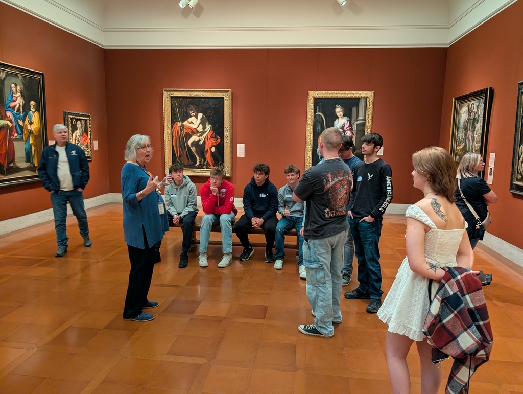 People looking at a docent while she talks about the art