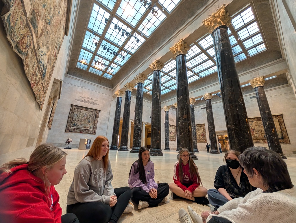 People looking at a docent while she talks about the art