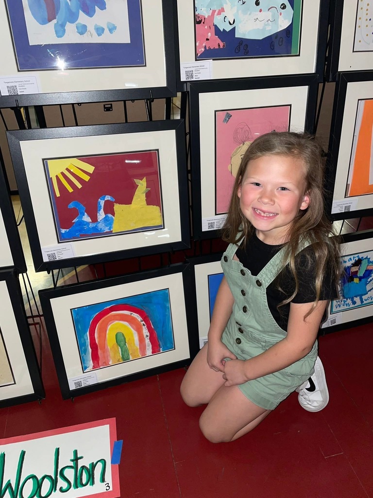 happy student next to her framed Artwork at the art show 