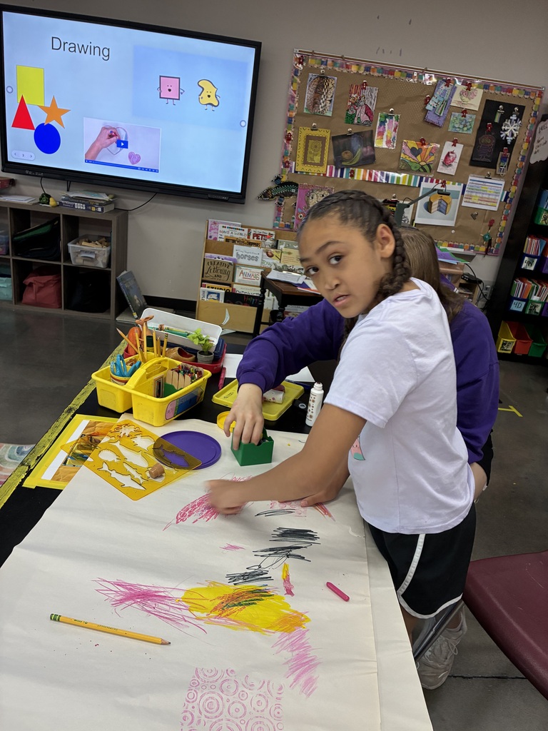 girl in white shirt coloring with pink and yellow on big paper. 