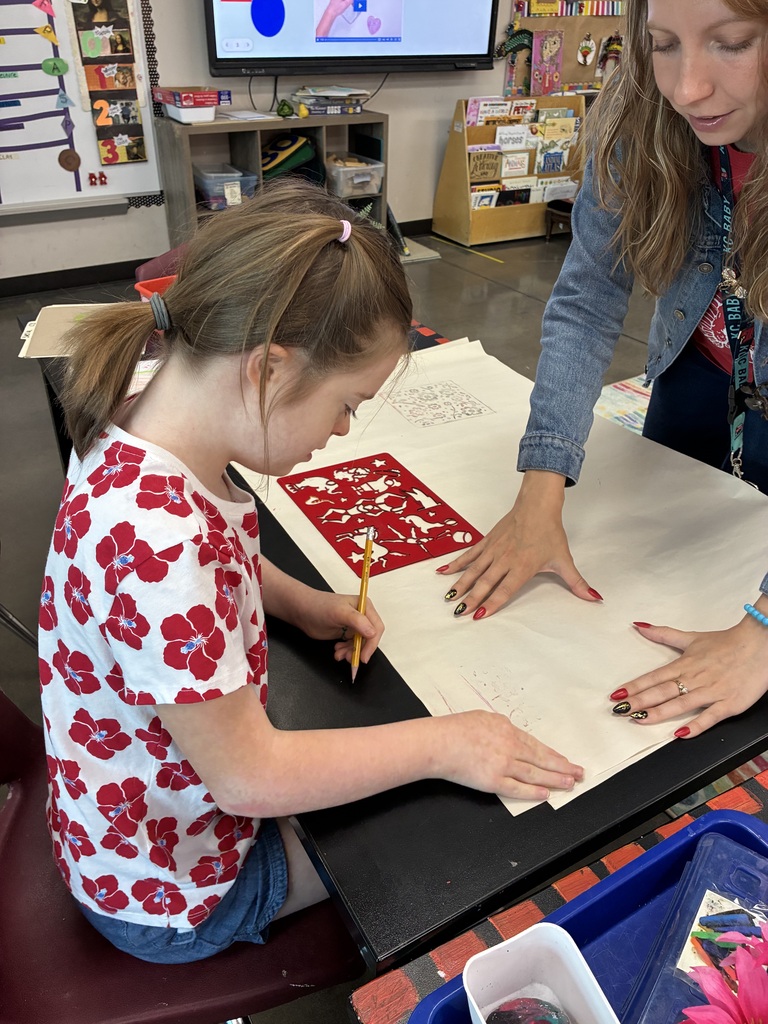 Student in shirt with red flowers tracing shapes and making textures on paper 