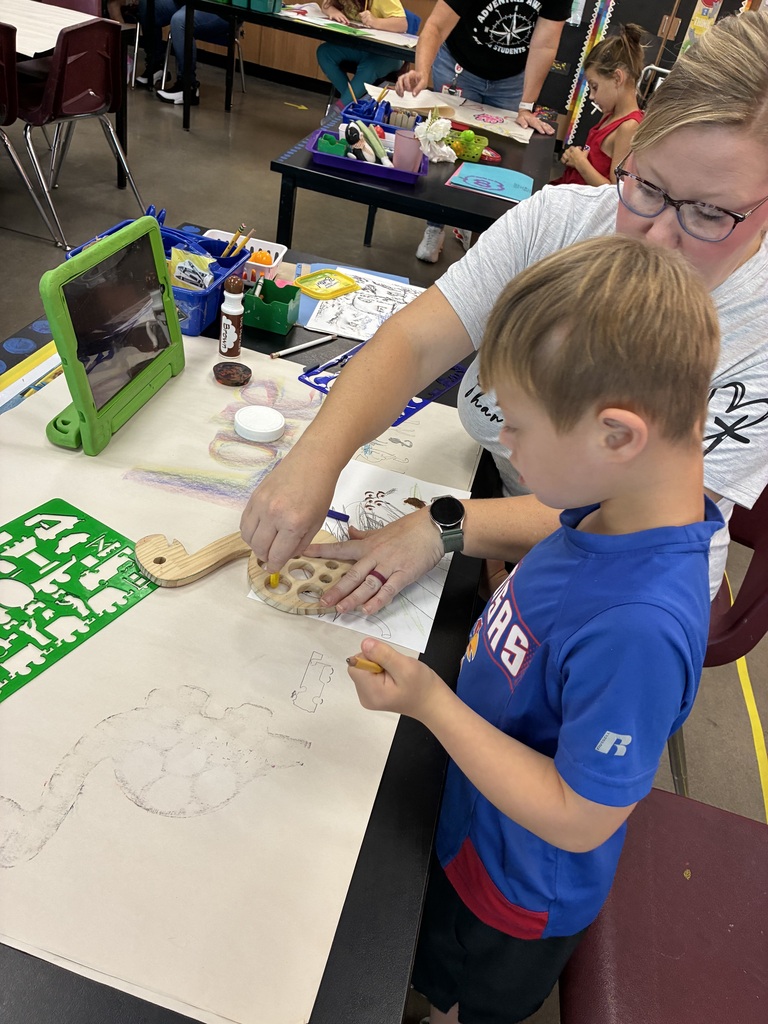student in blue shirt tracing a dinosaur