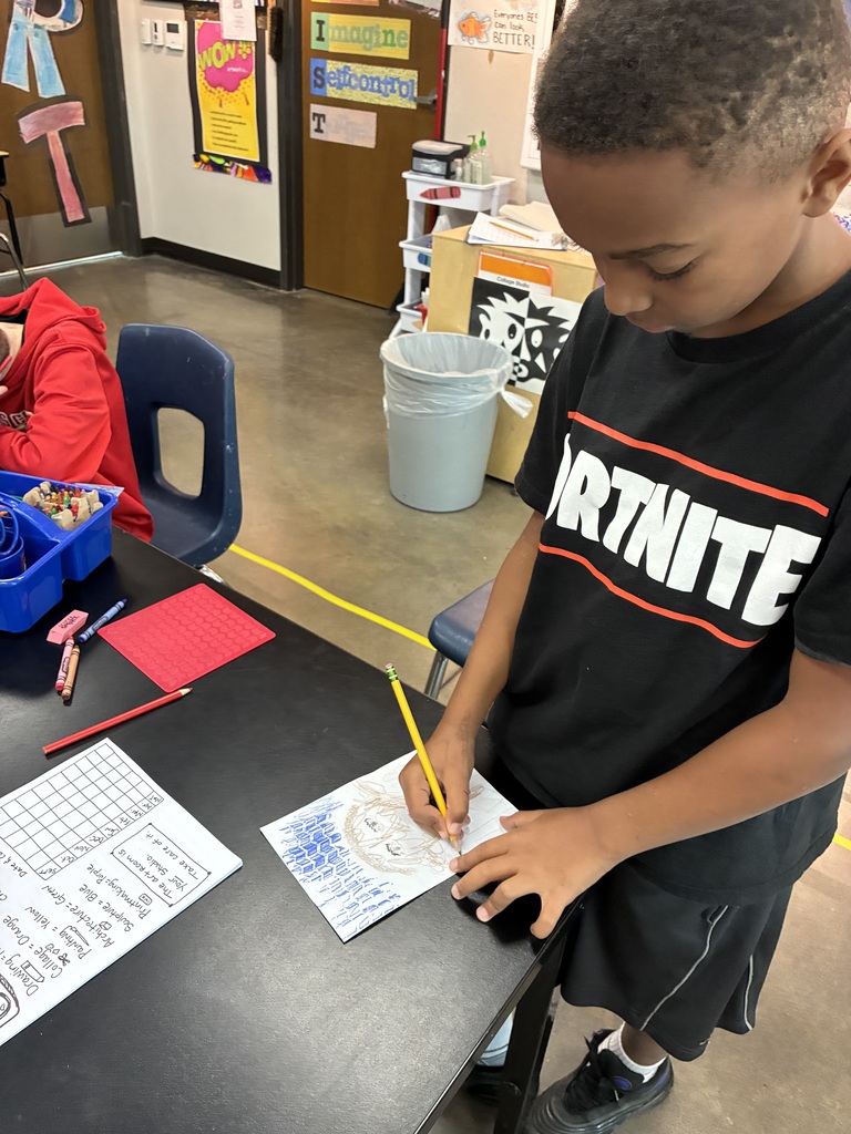 boy in black fortnite shirt is drawing a self portrait with a yellow pencil 