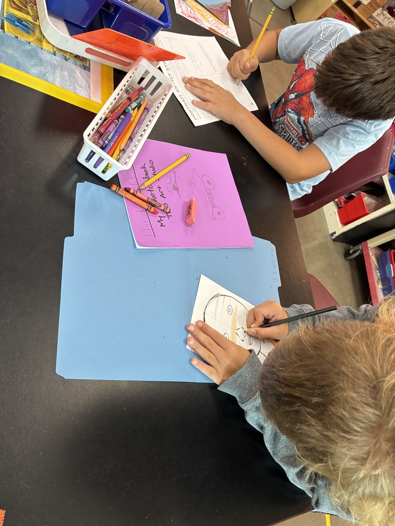 two boys are working on their self portrait. One boy is wearing a spiderman t-shirt 