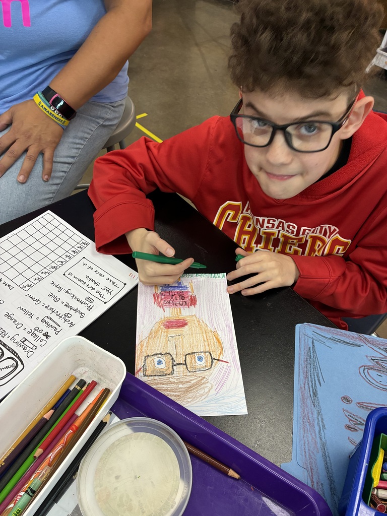 boy in glasses and red KC Chiefs shirt is drawing his self portrait 
