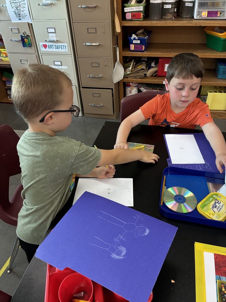 two boys drawing on folders and on their self portraits