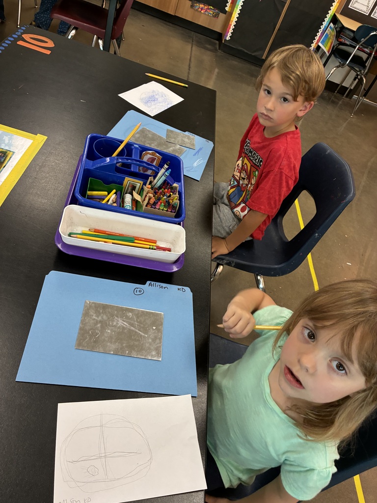 girl in green shirt and boy in red Mario shirt drawing self portraits