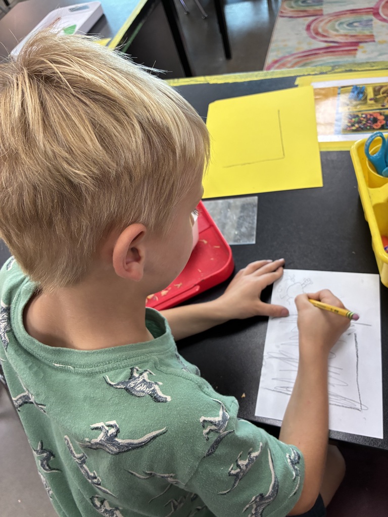 boy in dino shirt drawing self portrait