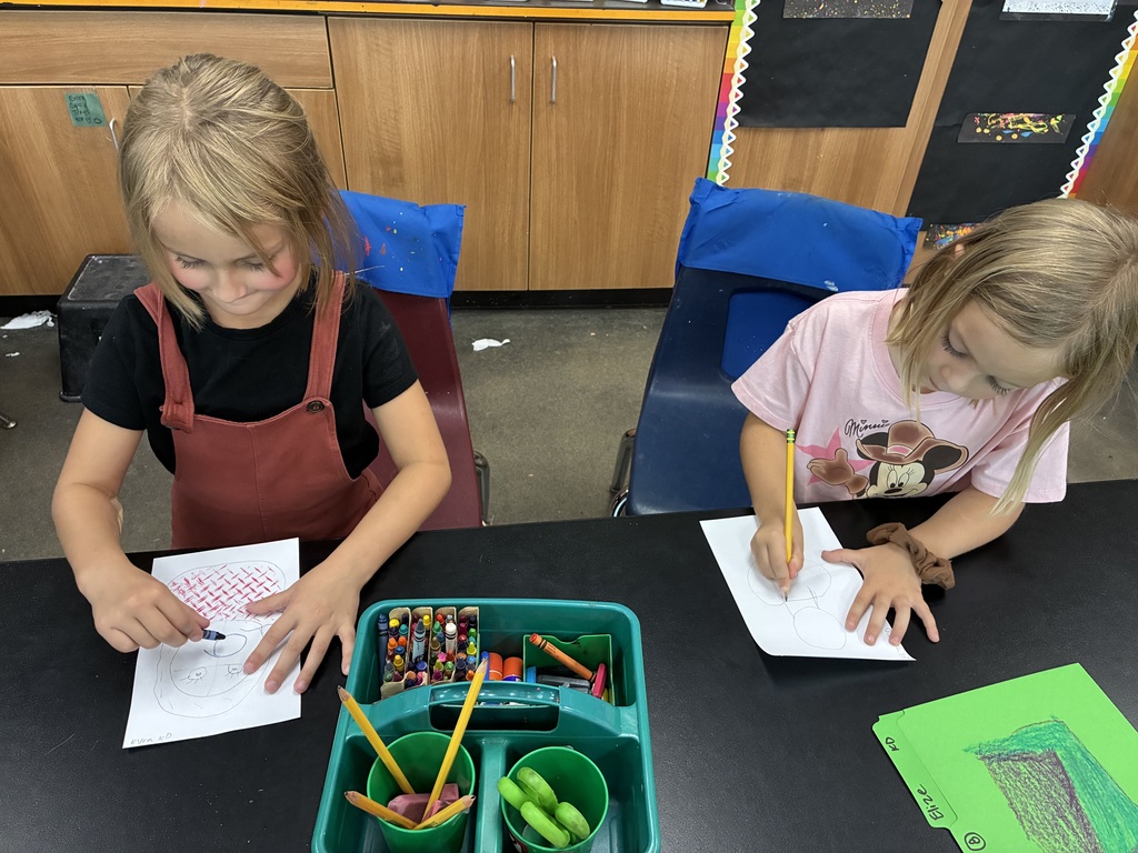girl in red jumper and girl in pink Disney shirt drawing self portraits