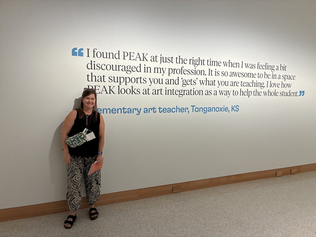 Mrs. Lawson in black shirt in front of a quote on the wall.