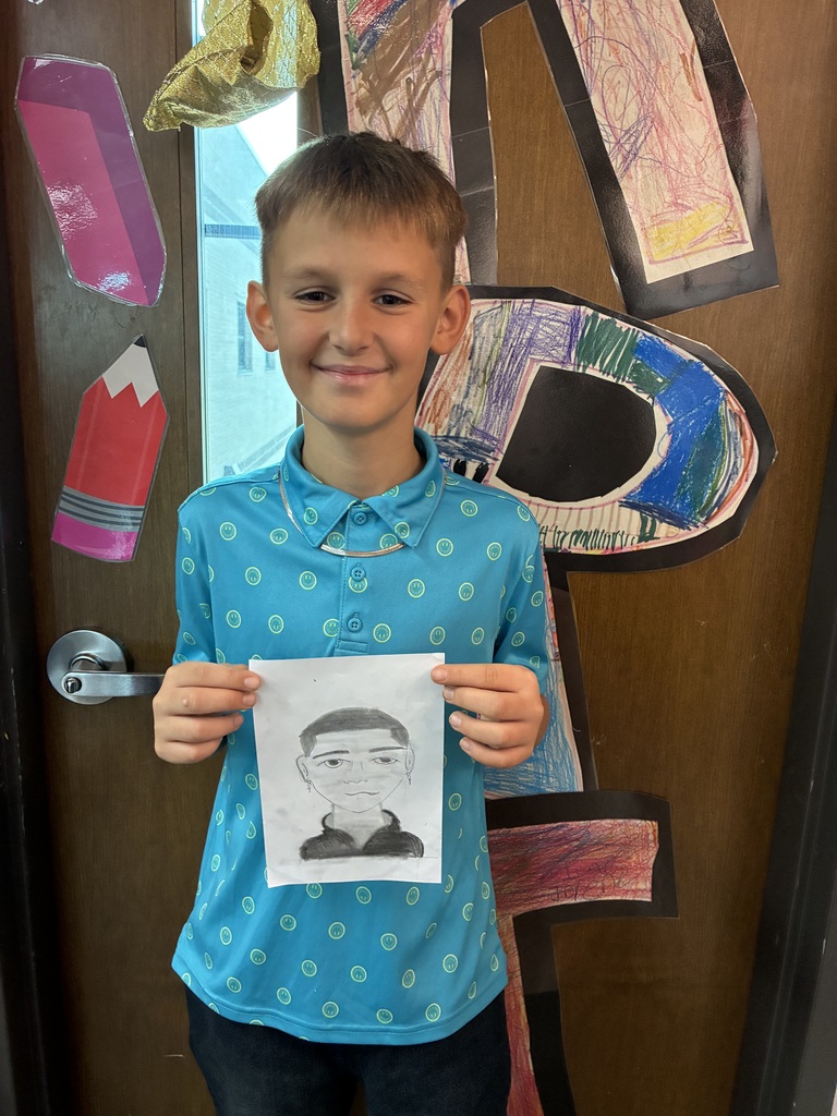 Student blue shirt holding his drawing of himself