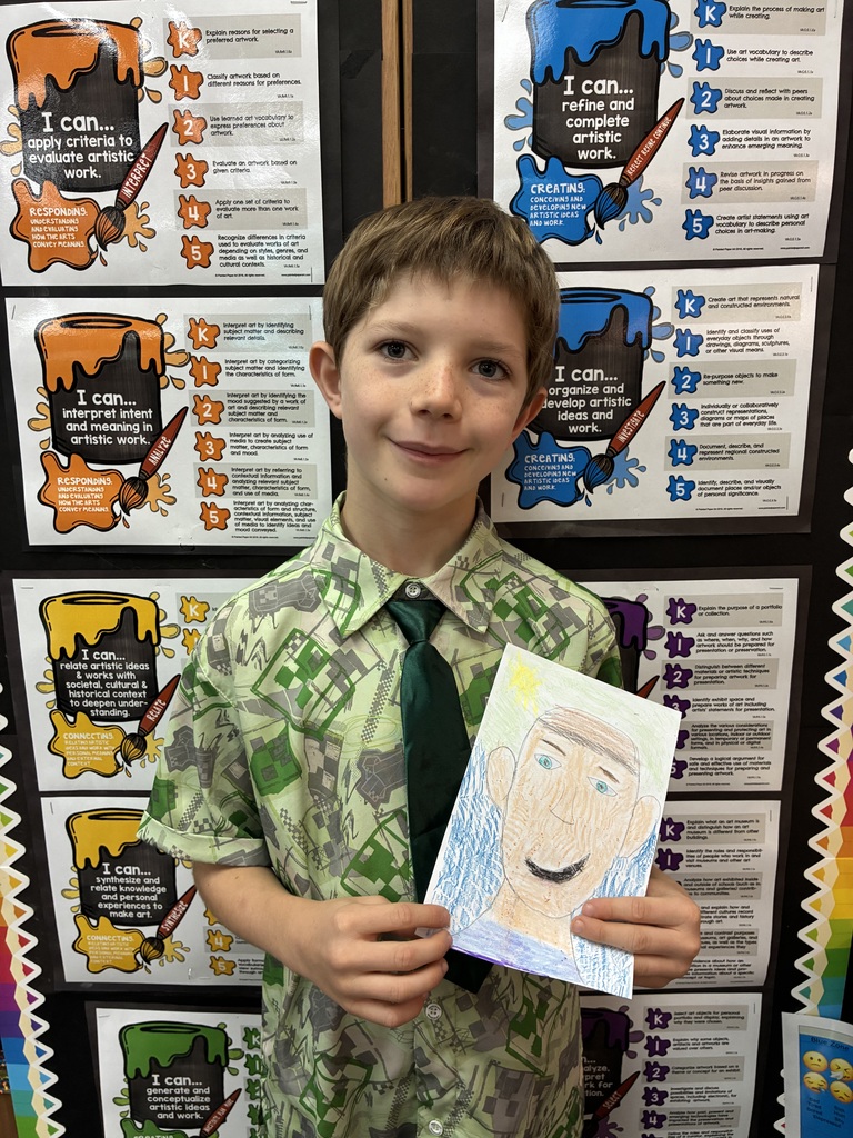 Student green shirt holding his drawing of himself