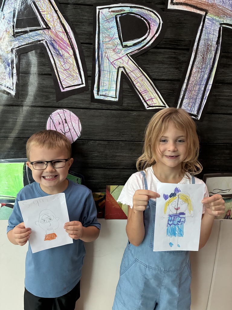 Students holding drawings of themselves